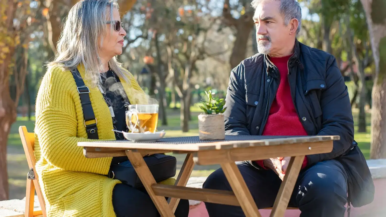 A woman and a man in their sixties talking over tea at an outdoor table